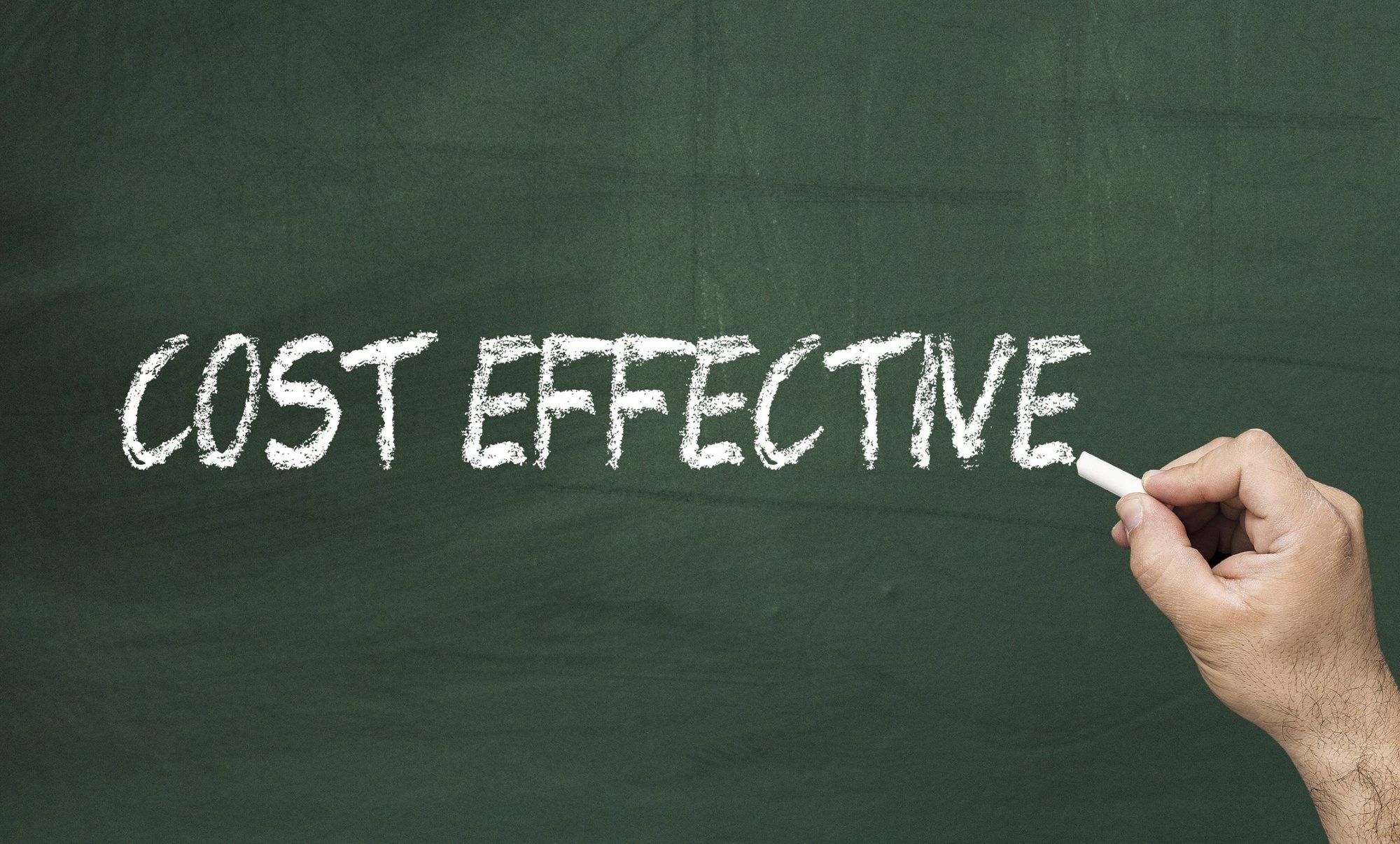 A hand is holding a piece of white chalk and is completing the words "Cost Effective" on a green chalkboard.