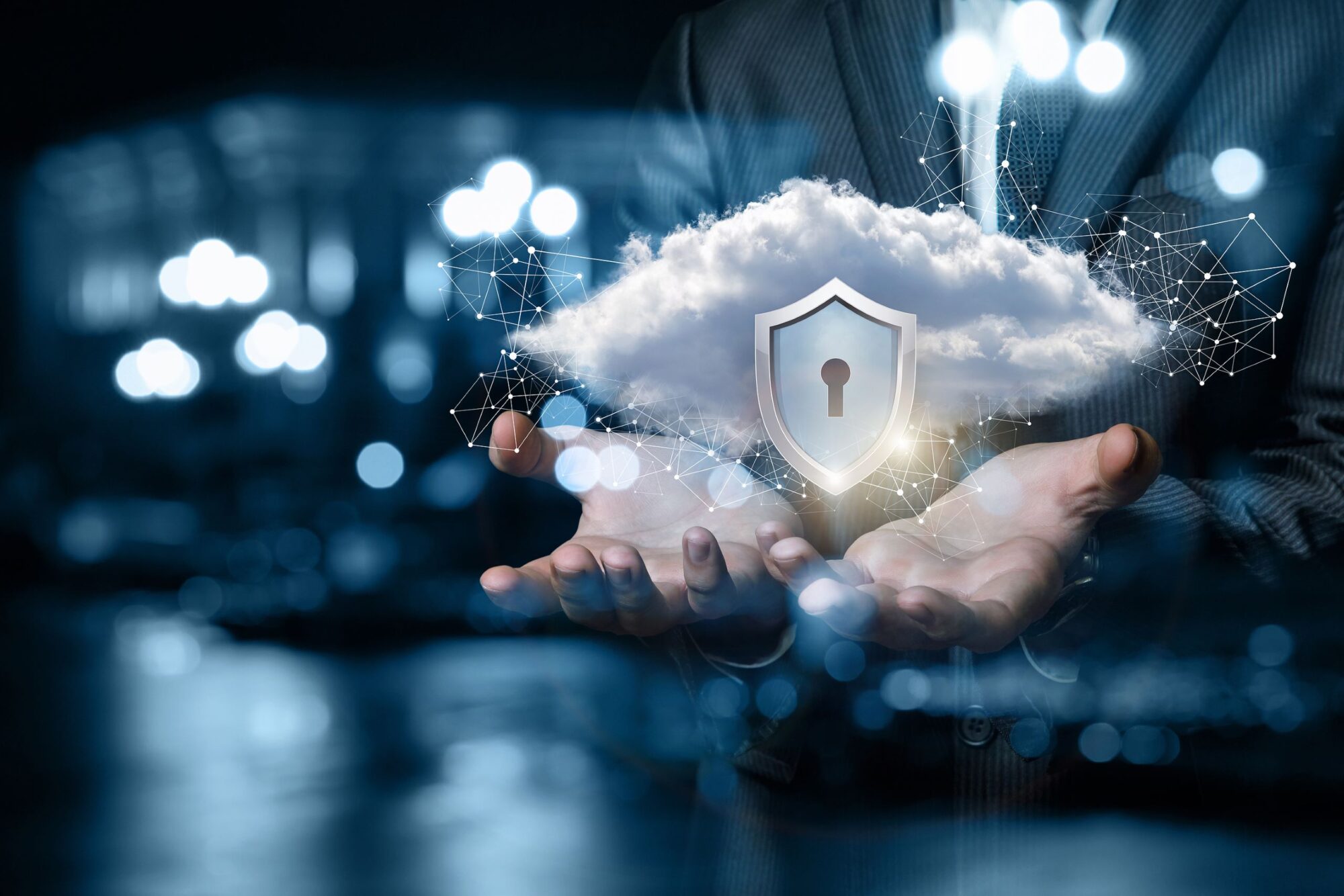 Hands of a business person are cupping a virtual cloud with an icon of a protection shield.